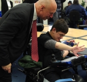 Sam shows Representative Tom Sannicandro how his DynaVox communication device works.