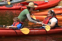 two people getting ready to go out in kayak with help from DCR staff