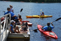 people on dock and in kayaks