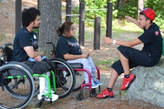 three people talk in the shade