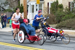 Two men pushing wheelchairs