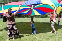 Kids and Adults play with large parachute.