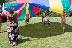 Kids and Adults play with large parachute.