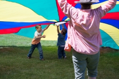 Kids and Adults play with large parachute.