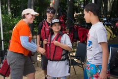 Three kids getting their life jackets on with DCR staff.