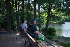 2 people sitting on a bench overlooking the pond