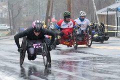 Photo of one women's wheelchair racer and 3 handcycle racers