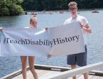two people holding Teach Disability History campaign banner