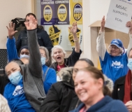 Several people with arms up, yelling indoors