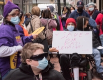 Person in a wheelchair with sign "Save our PCAs, let us live"