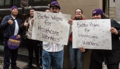 People with signs "Better Wages for Healthcare Workers"