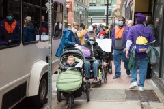 Protesters line up on the sidewalk, including Aurora with the youngest protestor