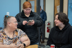 two women talking with third on her phone