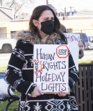 Woman with sign: Stop - Human RIghts NOT Holiday Lights