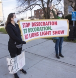Protestors: "Stop Desecration by Decoration. No Lions Light Show", and "Light Show Hell No"