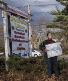 Woman in front of Lions Promotional sign with her own sign: You're on the Wrong Side of History