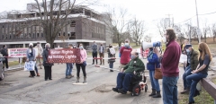 Alex Green speaks to protesters at Fernald.  Banner saying Human Rights Not Holiday Lights.