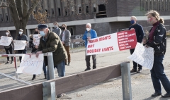 Protestors at Fernald - banner saying Human Rights Not Holiday Lights.  Sign saying "Don't"