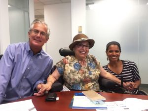 Judy Heumann with Michael Morris and Maggie Redden. In photo Michael, Judy and Maggie are smiling and holding hands.