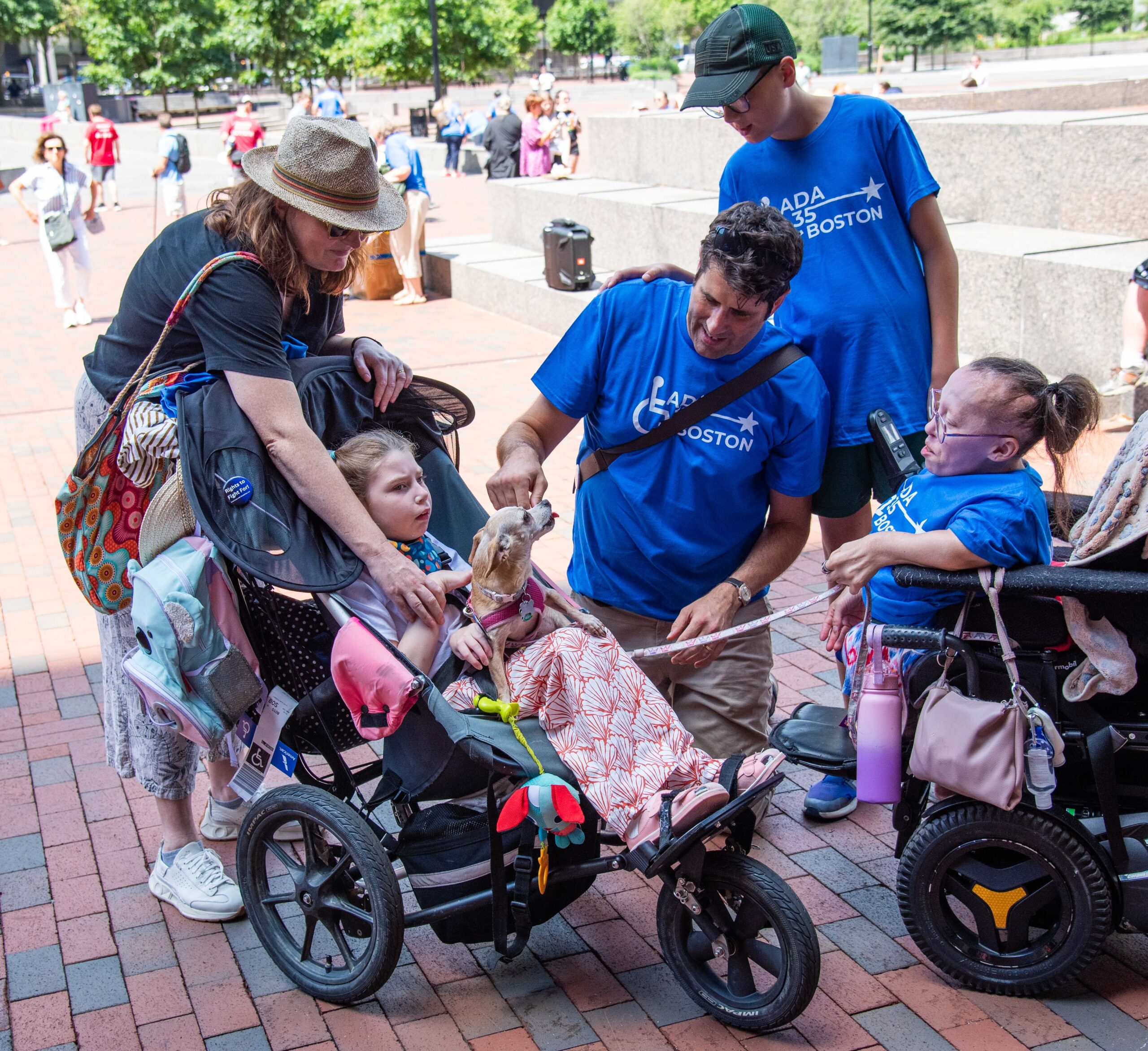 Young girl in wheelchair plays with woman in wheelchair's dog