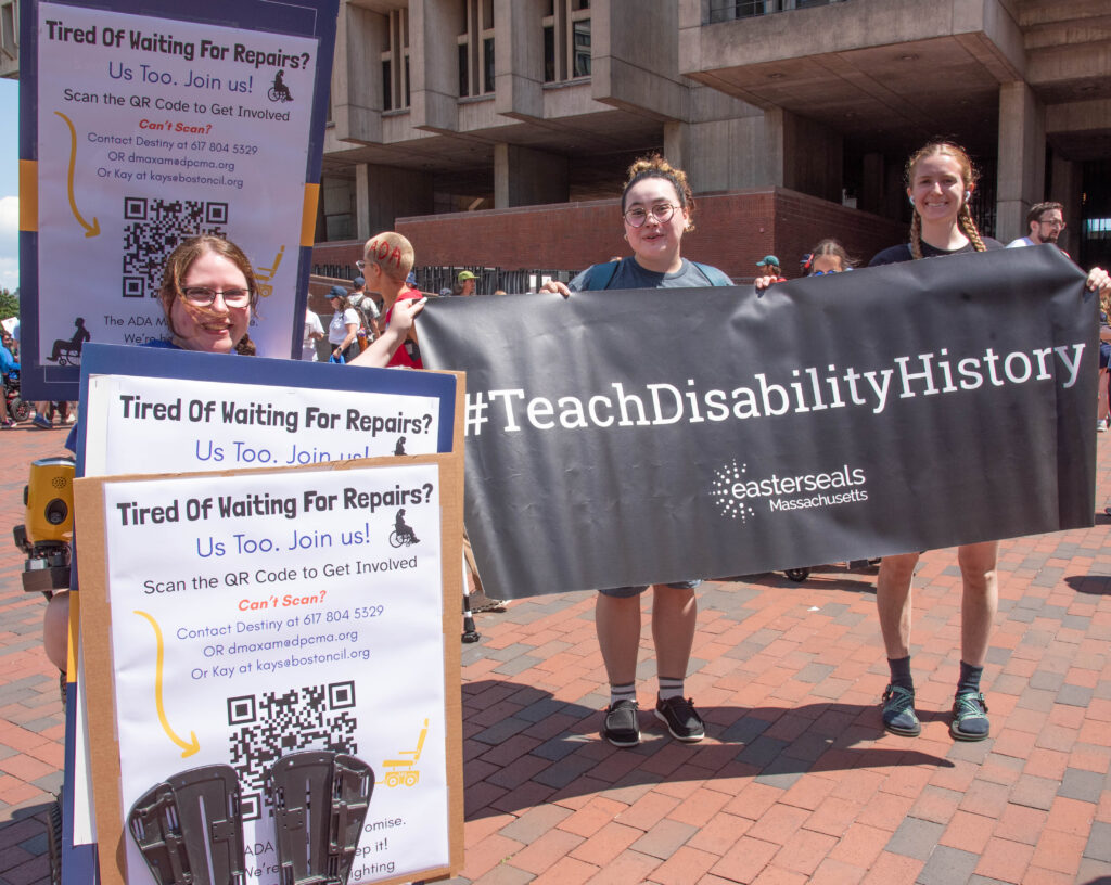 women with signs for wheelchair repair and teach disability History