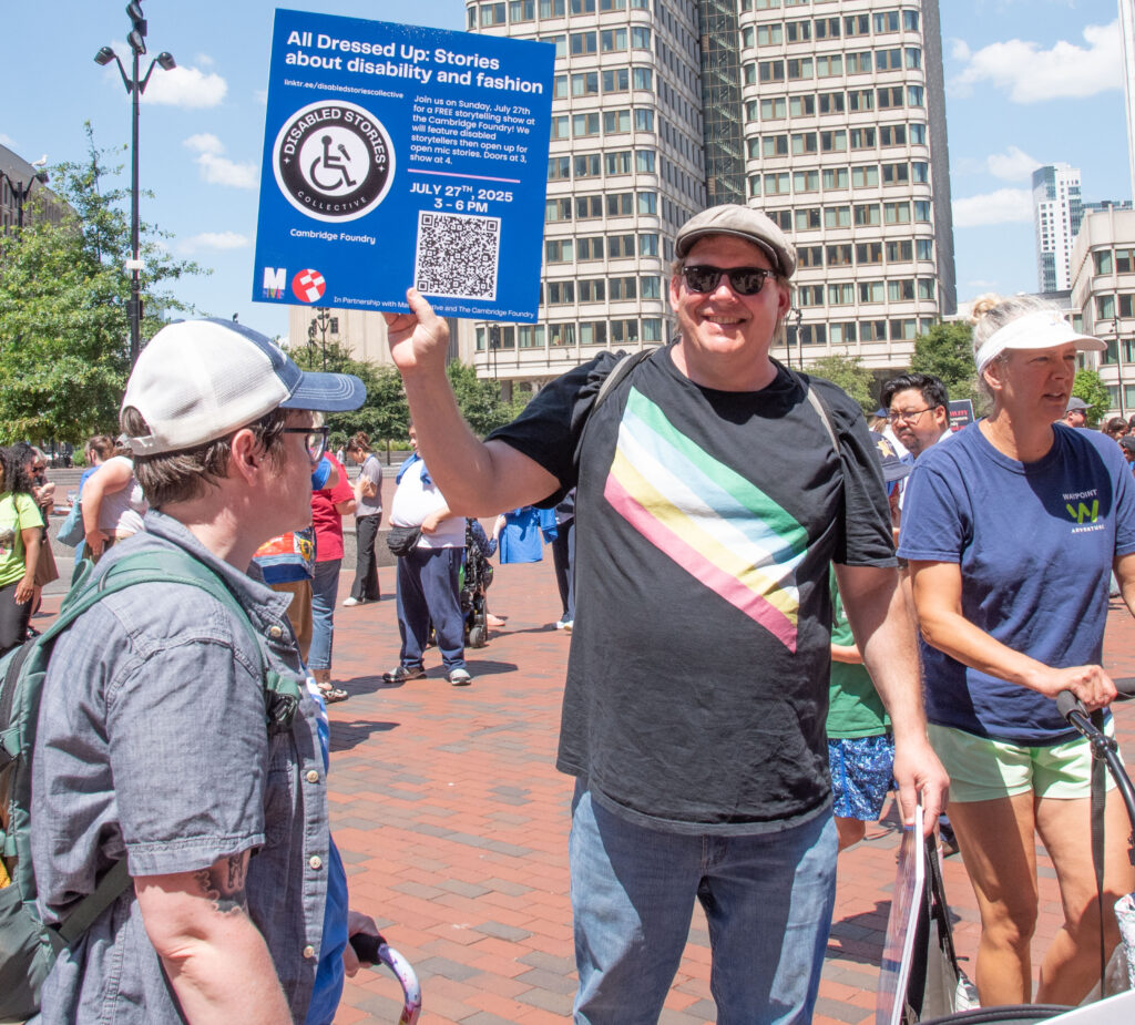 man with sign: All dressed up: Stories about disability and fashion